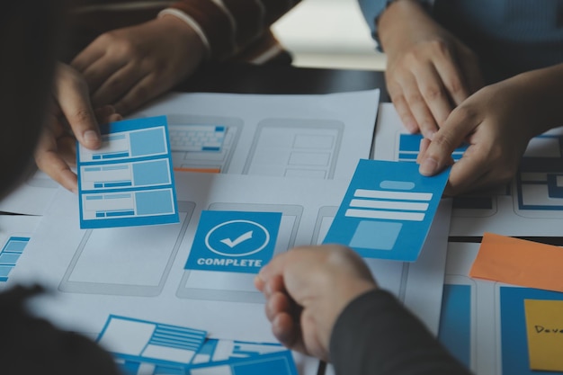 Close up ux developer and ui designer brainstorming about mobile app interface wireframe design on table with customer breif and color code at modern officeCreative digital development agency