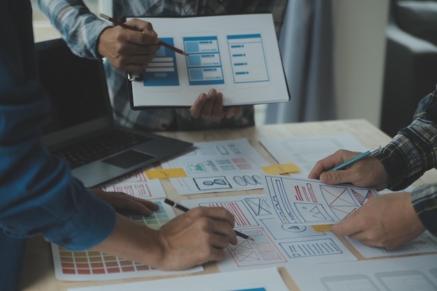 Close up ux developer and ui designer brainstorming about mobile app interface wireframe design on table with customer breif and color code at modern officeCreative digital development agency