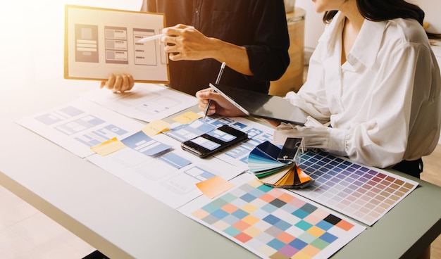 Close up ux developer and ui designer brainstorming about mobile app interface wireframe design on table with customer breif and color code at modern officeCreative digital development agency