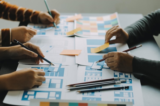 Close up ux developer and ui designer brainstorming about mobile app interface wireframe design on table with customer breif and color code at modern officeCreative digital development agency