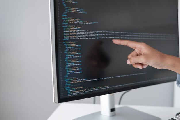 Close up view of programmer pointing to desktop computer with developing programming code trying to solve the problem