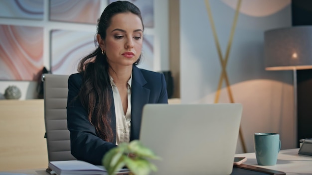 Closeup diligent businesswoman typing laptop in office serious woman writing