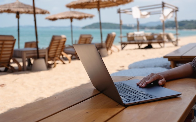 closeup of a woman working and touching on laptop touchpad on the beach