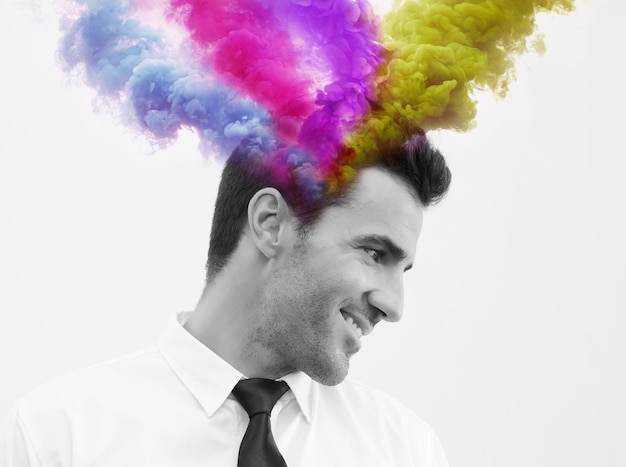 Colorful smoke emitting from head of smiling man against white background
