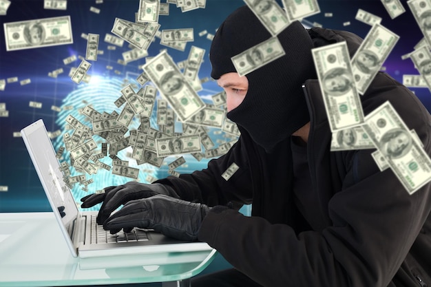 Composite image of robber sitting at desk hacking a laptop