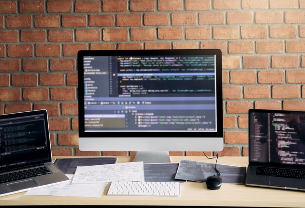 Computers on table against brick wall