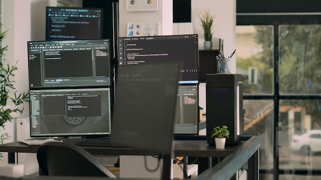 Computerskærme på skrivebordet kører programmeringskode dataalgoritmer i tomt kodningsrum. Database netværksservere cloud computing i software it agenturkontor, html scriptsprog.
