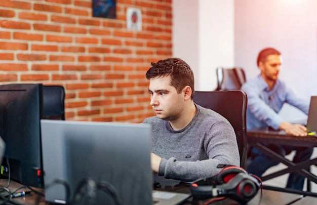 Concentrated at work Confident young man in smart casual wear working on laptop while sitting in an office with modern interior