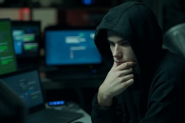 Cool hacker with hoodie working with computers