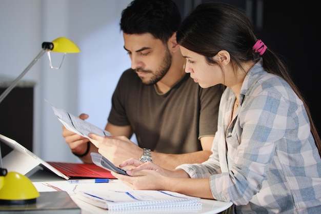 Couple analyzing financial bills on table at home