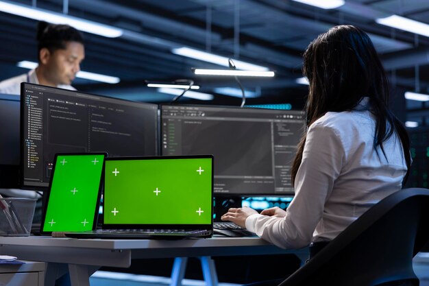 Coworkers in data center using green screen laptop and tablet