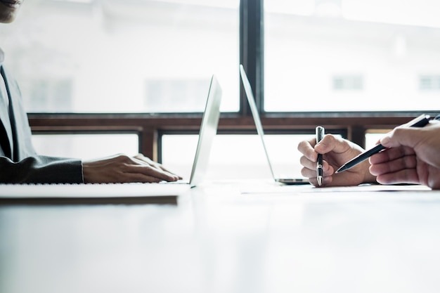 cropped hands of business people using laptop on table at office