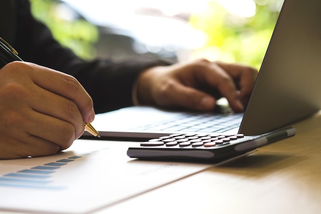 Cropped hands of business person using laptop at desk in office