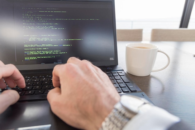 Cropped hands of business using laptop at desk in office