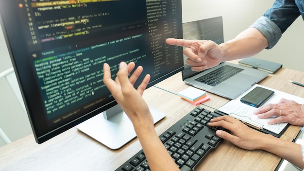 Cropped hands of coworkers discussing over computer in office