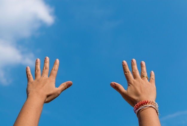 Cropped hands of people against blue sky