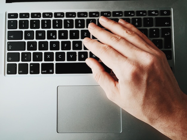 Cropped image of hand typing on laptop