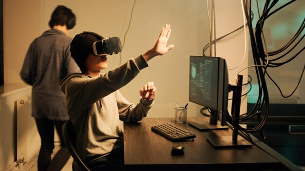 Cyber criminal working with 3d vr glasses to crack firewall encryption, using virtual reality headset to hack government system. Male hacker breaking network with malware and virus.