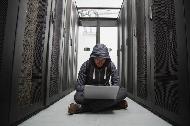 Cyber security. Skilled male hacker sitting on floor while cracking system