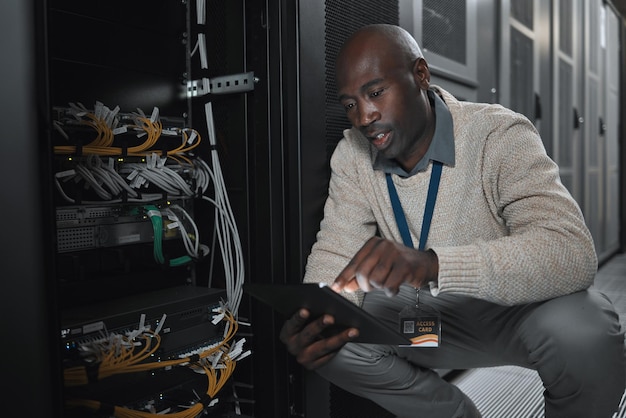 Data center or black man on tablet in server room on database maintenance or software update Cybersecurity it or startup male coder on technology for cloud computing programming or web networking
