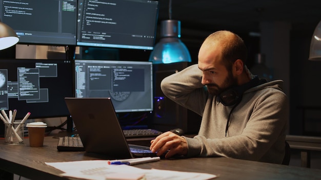 Database programer writing code and dealing with back pain, sitting at office and feeling spinal discomfort at night. App developer computing big data and coding html script on terminal window.