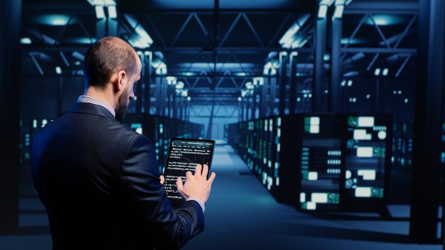 Datacenter engineer inspecting working server computers with web information on tablet, future digitalization. Modern IT administrator running diagnostics on networking connection. Tripod shot.