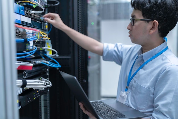 Datatekniker installerar nätverk i serverrumSystemunderhållsteknikerManlig ingenjör som arbetar i serverrum på ett modernt datacenter