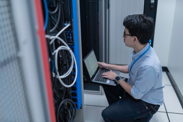 Datatekniker installerar nätverk i serverrumSystemunderhållsteknikerManlig ingenjör som arbetar i serverrum på ett modernt datacenter