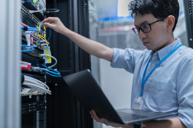 Datatekniker installerar nätverk i serverrumSystemunderhållsteknikerManlig ingenjör som arbetar i serverrum på ett modernt datacenter