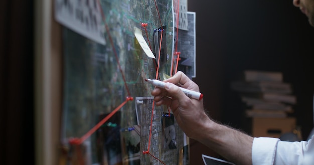 Detective at work connecting clues on an investigation board