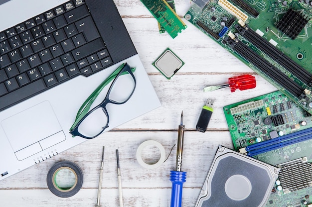 Directly above shot of laptop with mother board and eyeglasses on white table