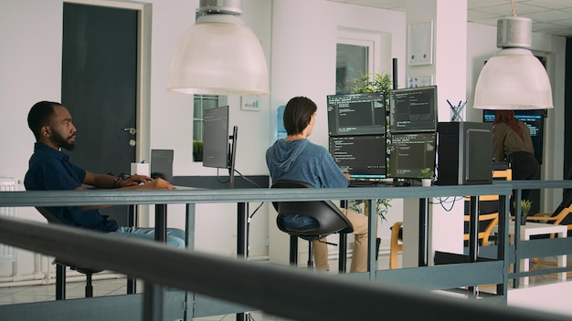 Diverse artificial intelligence programers typing system code and programming firewall server on multiple screens. IT developers working with coding algorithms, learning html language.