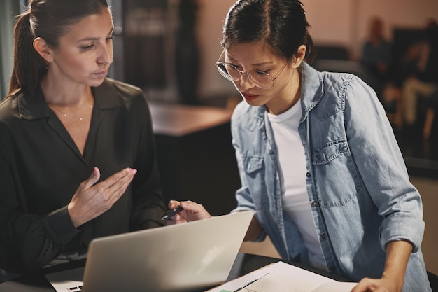Diverse businesswomen talking together over a laptop in an office