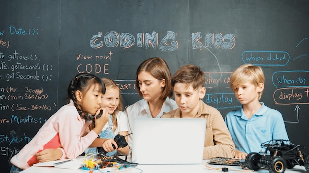 Diverse student writing engineering code while boy fixing board erudition