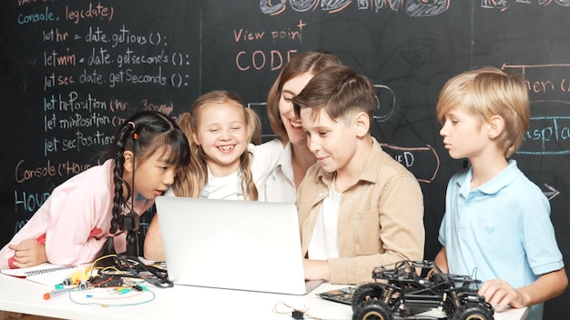 Diverse student writing engineering code while boy fixing board erudition