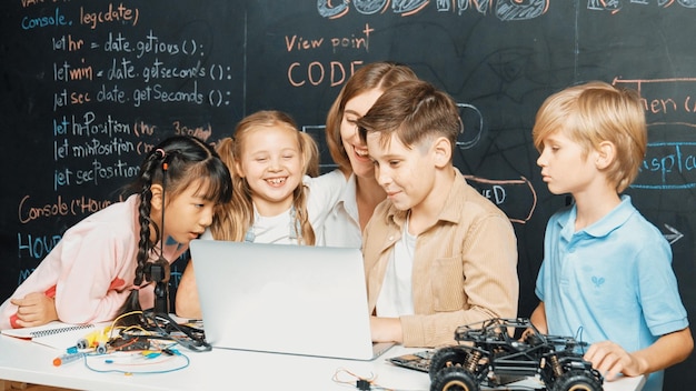 Diverse student writing engineering code while boy fixing board erudition