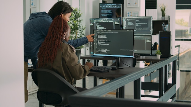 Diverse team af ai cloud-programmører taler om kodningsscript foran computeren, arbejder på server interface udvikling. Programmører laver teamwork for at planlægge html software sprog.