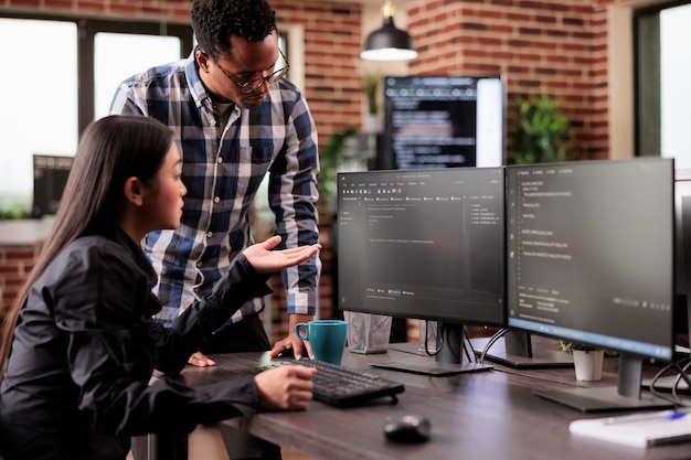 Diverse team of system engineers developing html code and cloud computing in it development agency. Asian software developer typing on keyboard to create artificial intelligence script.
