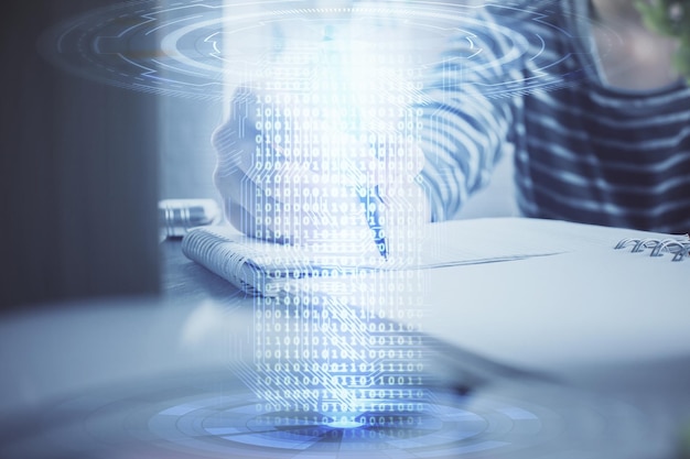 Dobbelteksponering af hænder, der tager noter, med digitale kodningsikoner. Computerlæringskoncept