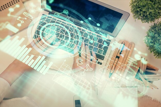 Dobbelteksponering af kvindehænder, der arbejder på computer, og hologramtegning med finansielt tema. Top View Business concept