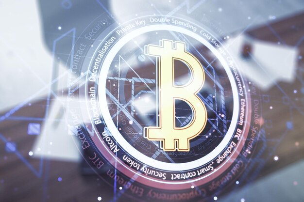 Double exposure of creative Bitcoin symbol and modern desktop with laptop on background Cryptocurrency concept
