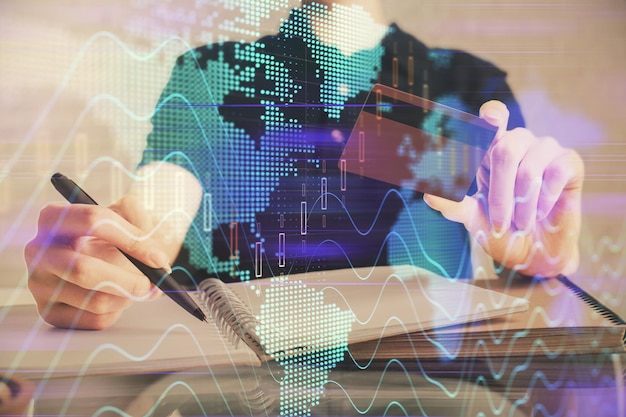Double exposure of man hands holding a credit card and Forex graph drawing Stock trading and digital fintech in Internet Ecommerce concept
