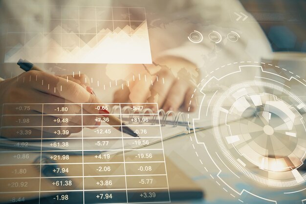 Double exposure of womans hands making notes with forex graph hologram Concept technical analysis