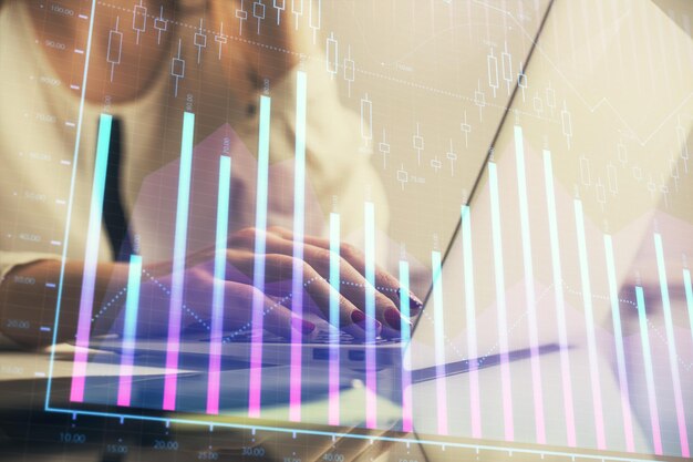 Dubbelexponering av kvinnohänder som skriver på dator och finansiell graf hologramritning Aktiemarknadsanalyskoncept