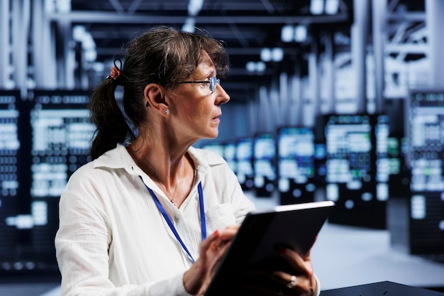 Elderly efficient admin updating data center units writing intricate binary code scripts on tablet using programming to fortify cybersecurity in technically advanced server farm