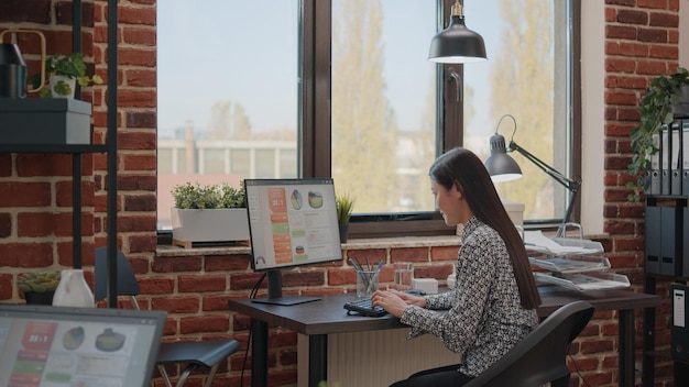 Employee working with business charts design on computer. Entrepreneur using data analysis to plan project and marketing strategy in startup office, helping with company growth.
