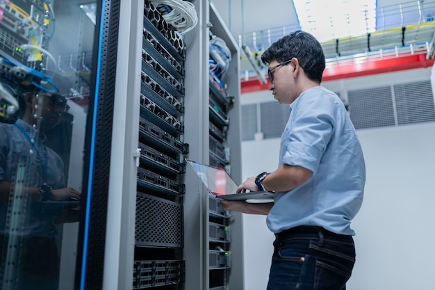 En computertekniker opsætter netværk i serverrummet. Systemvedligeholdelsestekniker. Mandlig tekniker arbejder i serverrum i et moderne datacenter