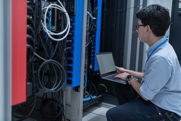 En computertekniker opsætter netværk i serverrummet. Systemvedligeholdelsestekniker. Mandlig tekniker arbejder i serverrum i et moderne datacenter