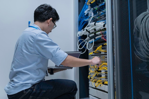 En computertekniker opsætter netværk i serverrummet. Systemvedligeholdelsestekniker. Mandlig tekniker arbejder i serverrum i et moderne datacenter