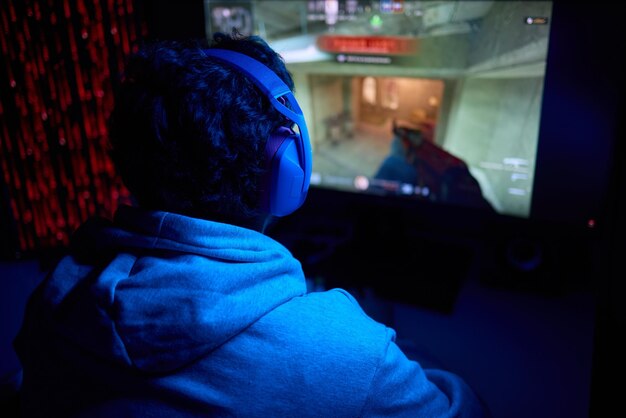 En programmør arbejder sent om natten på en computerskærm med kodning og bruger en smartphone-app